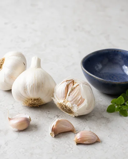 Fresh garlic bulbs and cloves beside a cobalt-blue bowl
