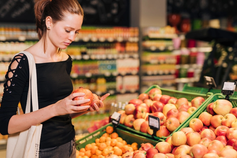 A woman carefully checking her grocery list in the produce section during the low FODMAP elimination phase.
